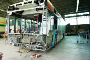 Ein verunfallter Bus steht in einer Halle und steht bereit für eine Unfallinstandsetzung.